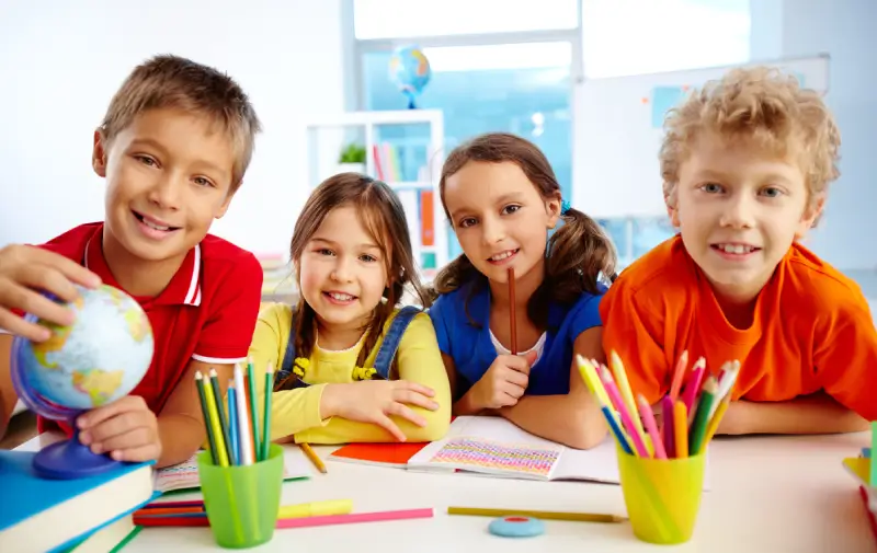 school kids at a desk smiling